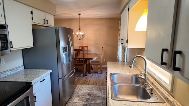 606 W Clover Dr, Clinton, MO 64735 - kitchen with a sink, appliances with stainless steel finishes, a chandelier, white cabinets, and dark wood-style floors