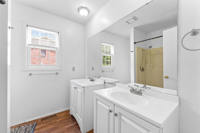 111-141 Gooseberry Ct, Branson, MO 65616 - bathroom with a textured ceiling, wood finished floors, two vanities, a shower, and baseboards