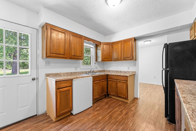 111-141 Gooseberry Ct, Branson, MO 65616 - kitchen featuring dishwashing machine, freestanding refrigerator, a textured ceiling, brown cabinets, and light countertops