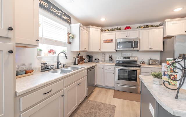 205 Seigenbein Rd, Saint Robert, MO 65584 - kitchen featuring stainless steel appliances, a sink, light countertops, light wood-style floors, and white cabinets