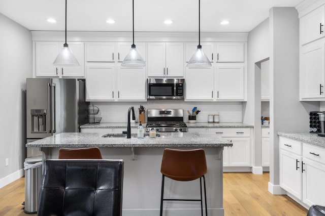 1816 N Bristol Ave, Springfield, MO 65802 - kitchen with stainless steel appliances, a sink, decorative backsplash, a kitchen bar, and white cabinets