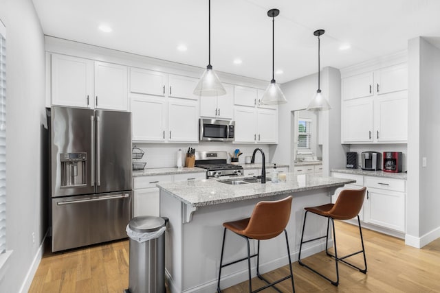 1816 N Bristol Ave, Springfield, MO 65802 - kitchen featuring stainless steel appliances, a sink, white cabinets, a kitchen breakfast bar, and light wood-type flooring