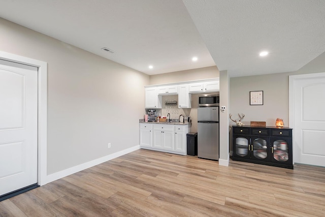 2025 Diego Ct, Bolivar, MO 65613 - indoor wet bar with appliances with stainless steel finishes, light wood finished floors, recessed lighting, baseboards, and tasteful backsplash