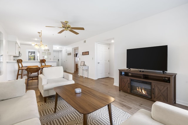 128 Bunker Ridge Rd Unit 2, Branson, MO 65616 - living area with light wood-style floors, a ceiling fan, a chandelier, and baseboards