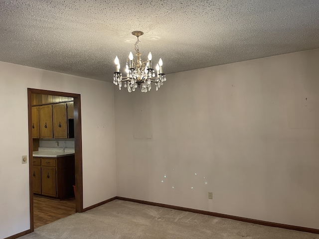 641 N Claud Ave, Bolivar, MO 65613 - spare room featuring a chandelier, light carpet, baseboards, and a textured ceiling