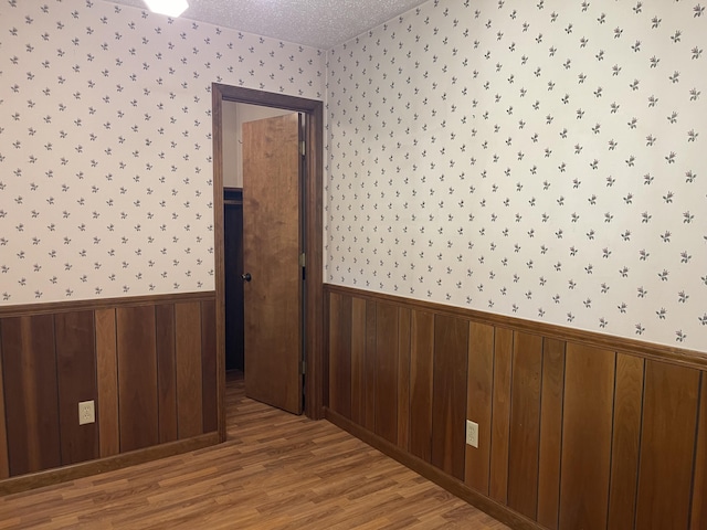 641 N Claud Ave, Bolivar, MO 65613 - spare room featuring wallpapered walls, wainscoting, wood finished floors, and a textured ceiling