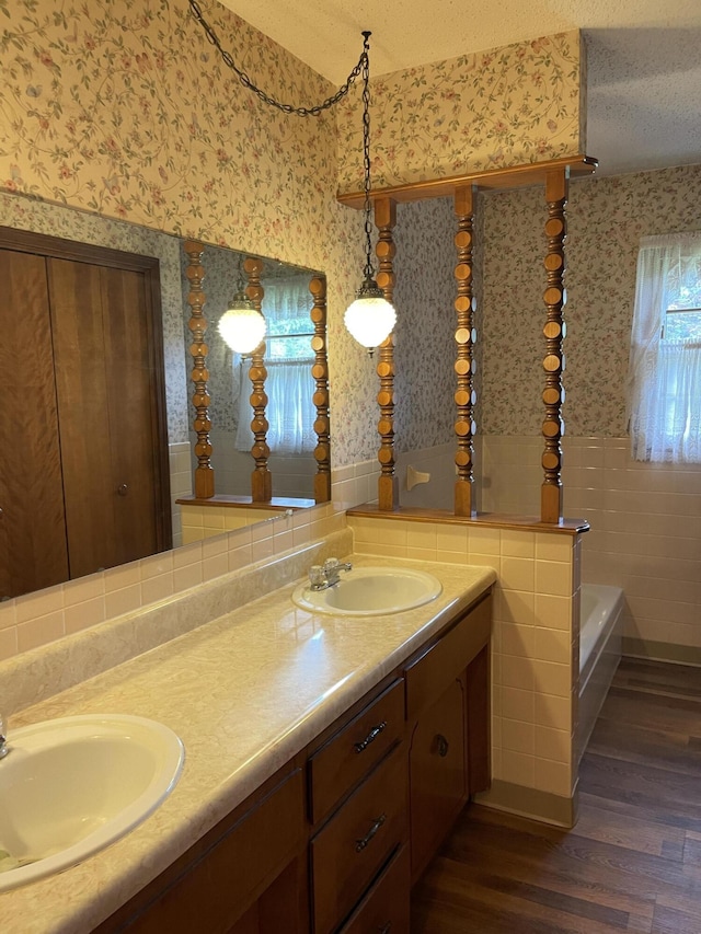 641 N Claud Ave, Bolivar, MO 65613 - bathroom featuring wallpapered walls, wood finished floors, double vanity, a garden tub, and a wainscoted wall