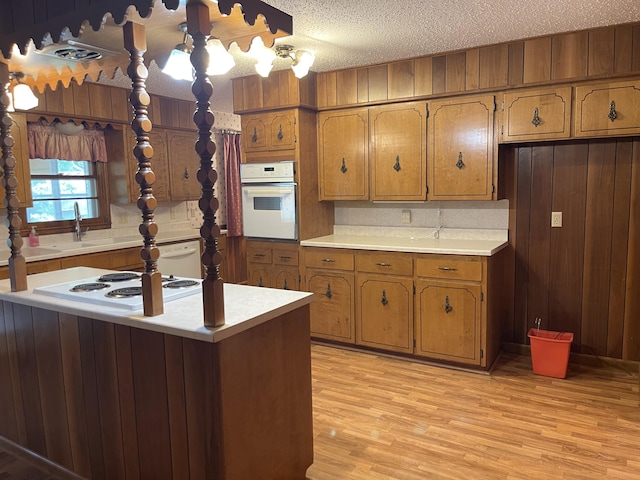 641 N Claud Ave, Bolivar, MO 65613 - kitchen with white appliances, brown cabinetry, light countertops, light wood finished floors, and a textured ceiling