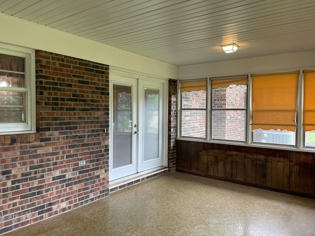 641 N Claud Ave, Bolivar, MO 65613 - unfurnished sunroom with healthy amount of natural light, french doors, carpet floors, brick wall, and wooden walls