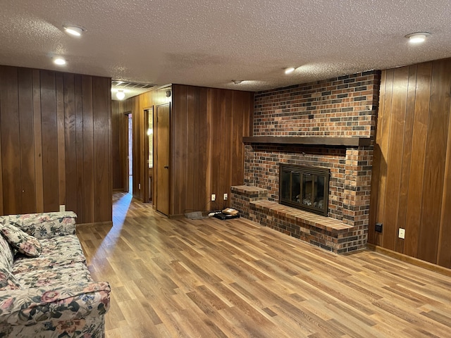 641 N Claud Ave, Bolivar, MO 65613 - living room with wood finished floors, wooden walls, a textured ceiling, a brick fireplace, and baseboards