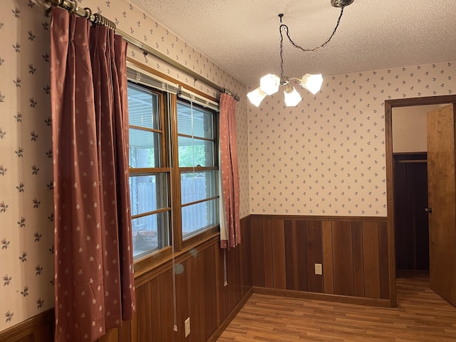 641 N Claud Ave, Bolivar, MO 65613 - unfurnished dining area featuring a chandelier, light wood finished floors, wainscoting, a textured ceiling, and plenty of natural light