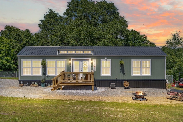 132 Nature Trail Ln, Noel, MO 64854 - back of property at dusk with an outdoor fire pit, metal roof, and a lawn