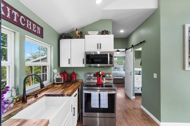 132 Nature Trail Ln, Noel, MO 64854 - kitchen featuring appliances with stainless steel finishes, wooden counters, a barn door, vaulted ceiling, and white cabinets