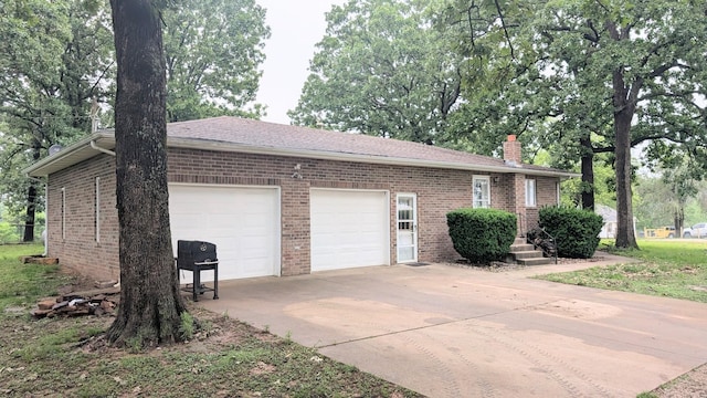 9550 S 325th Rd, El Dorado Springs, MO 64744 - view of home's exterior featuring driveway, an attached garage, brick siding, and a chimney