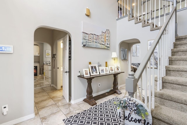 3909 W Eaglecrest St, Battlefield, MO 65619 - tiled entrance foyer with arched walkways, stairway, baseboards, a high ceiling, and a glass covered fireplace
