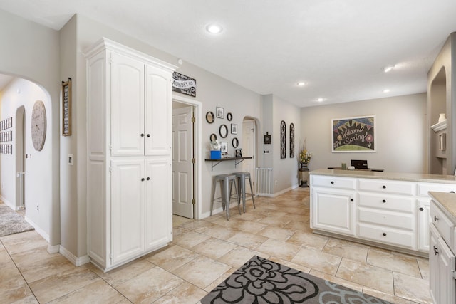 3909 W Eaglecrest St, Battlefield, MO 65619 - kitchen featuring white cabinetry, arched walkways, a peninsula, recessed lighting, and baseboards