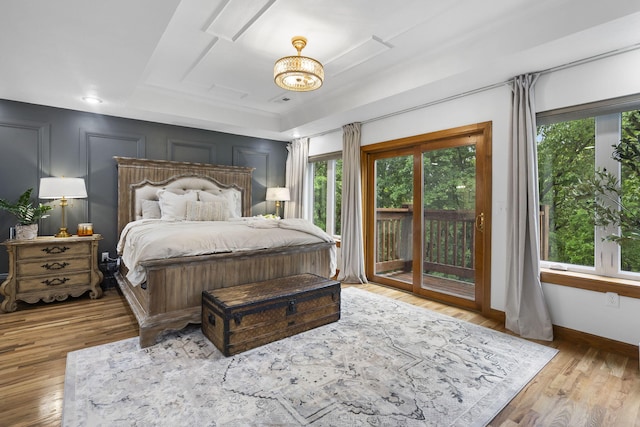 95 Highland Ct, Strafford, MO 65757 - bedroom featuring access to outside, wood finished floors, baseboards, a tray ceiling, and a chandelier