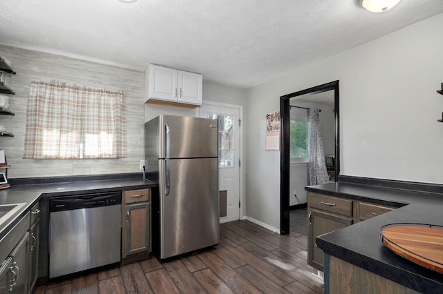 3625 S Moreland Ave, Springfield, MO 65807 - kitchen featuring appliances with stainless steel finishes, dark countertops, dark wood-style flooring, white cabinets, and baseboards
