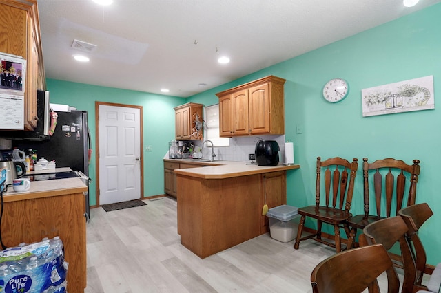 2852 S Pinehurst Ave, Springfield, MO 65807 - kitchen with light wood-style floors, a peninsula, light countertops, backsplash, and a breakfast bar