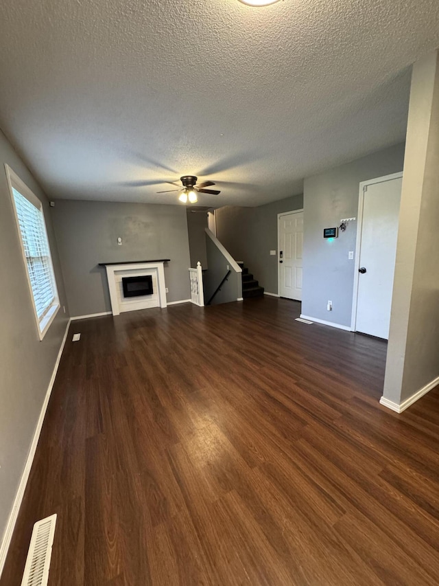 2201 S 14th St, Ozark, MO 65721 - unfurnished living room featuring baseboards, a textured ceiling, wood finished floors, a ceiling fan, and a fireplace