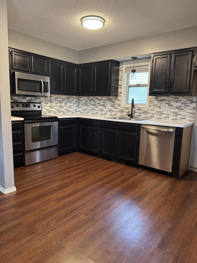 2201 S 14th St, Ozark, MO 65721 - kitchen with appliances with stainless steel finishes, dark cabinetry, a sink, light countertops, and a textured ceiling