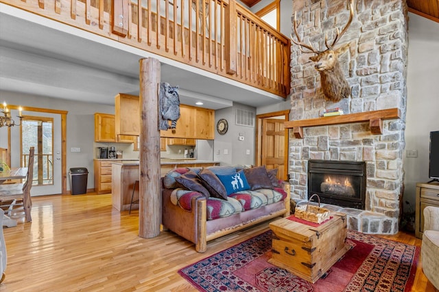 60 Mayberry Cir, Branson West, MO 65737 - living room with light wood-style flooring, a stone fireplace, a chandelier, and a towering ceiling