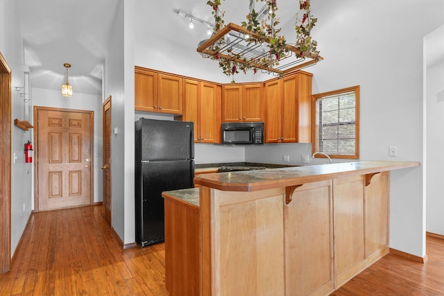160 Village Trl, Indian Point, MO 65616 - kitchen featuring black appliances, a peninsula, light wood-type flooring, a kitchen breakfast bar, and baseboards