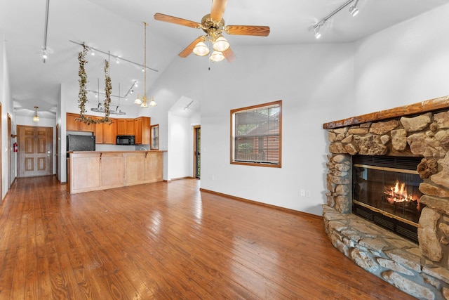 160 Village Trl, Indian Point, MO 65616 - unfurnished living room featuring rail lighting, high vaulted ceiling, a stone fireplace, hardwood / wood-style flooring, and a ceiling fan