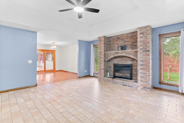 1007 Bryce Ln, Nixa, MO 65714 - unfurnished living room with a raised ceiling, a brick fireplace, baseboards, and a ceiling fan