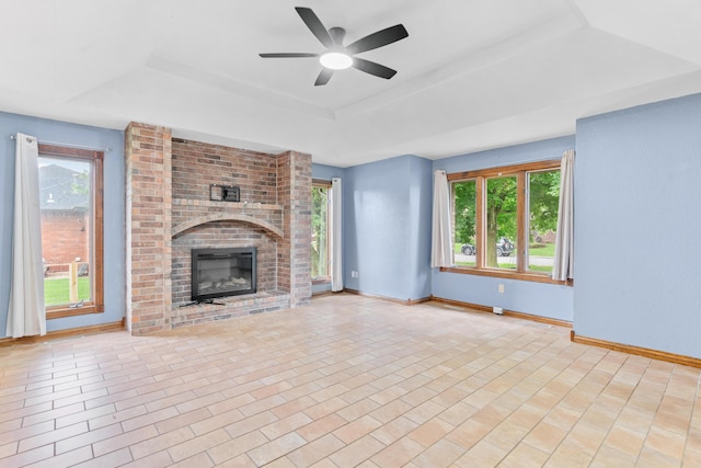 1007 Bryce Ln, Nixa, MO 65714 - unfurnished living room featuring a raised ceiling, baseboards, a fireplace, and ceiling fan