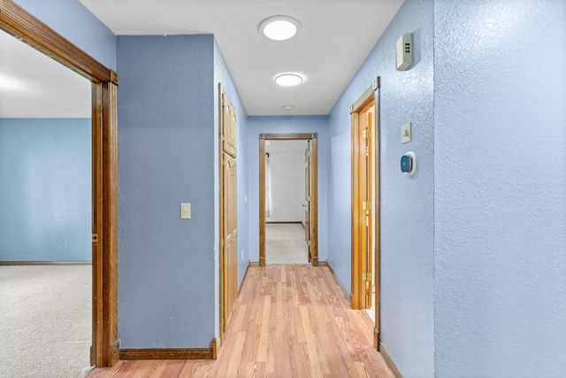 1007 Bryce Ln, Nixa, MO 65714 - hall featuring a textured wall, light wood-style flooring, and baseboards