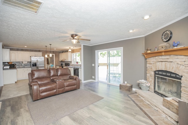 4857 S 101st Rd, Bolivar, MO 65613 - living area featuring ceiling fan, a textured ceiling, light wood-style floors, crown molding, and a stone fireplace