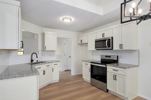 511 W Chestnut Rd, Nixa, MO 65714 - kitchen featuring appliances with stainless steel finishes, a sink, light wood-type flooring, and decorative backsplash