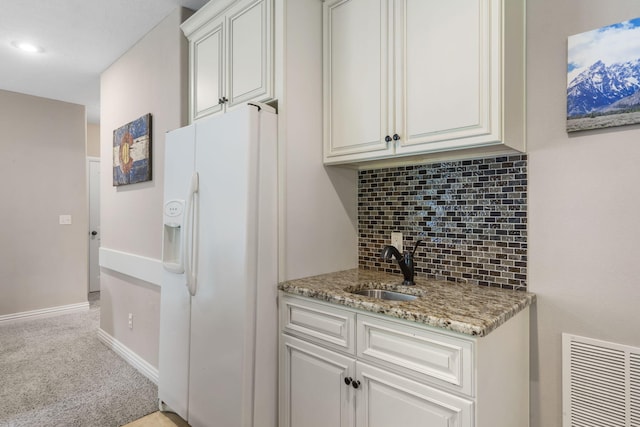 5142 S Burrows Ave, Springfield, MO 65810 - kitchen with white refrigerator with ice dispenser, a sink, light carpet, backsplash, and light stone counters
