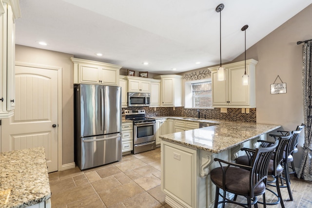 5142 S Burrows Ave, Springfield, MO 65810 - kitchen with appliances with stainless steel finishes, cream cabinets, decorative backsplash, a peninsula, and recessed lighting