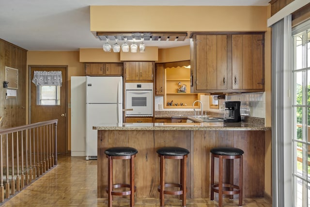 39 James River Rd, Kimberling City, MO 65686 - kitchen featuring white appliances, brown cabinetry, a peninsula, decorative backsplash, and open shelves