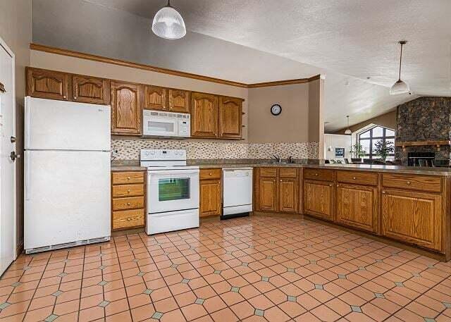 350 S Wildwood Dr Unit B-11, Branson, MO 65616 - kitchen featuring white appliances, lofted ceiling, brown cabinetry, pendant lighting, and backsplash