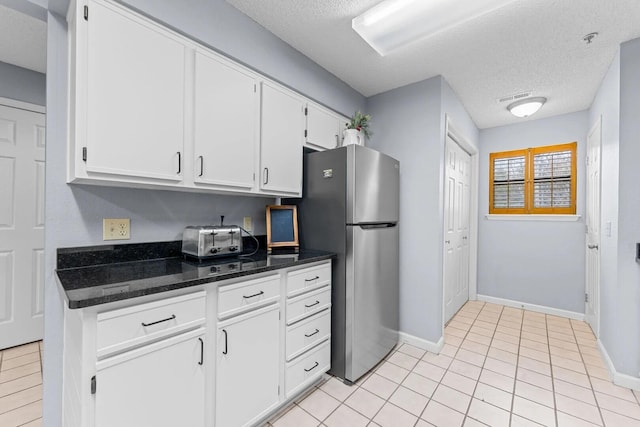 350 S Wildwood Dr Unit B-11, Branson, MO 65616 - kitchen with freestanding refrigerator, a textured ceiling, white cabinetry, baseboards, and dark stone counters