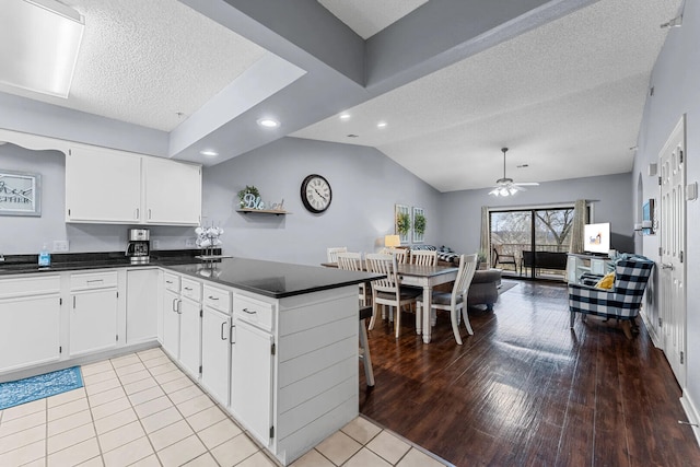 350 S Wildwood Dr Unit B-11, Branson, MO 65616 - kitchen with dark countertops, a peninsula, a textured ceiling, a ceiling fan, and white cabinetry
