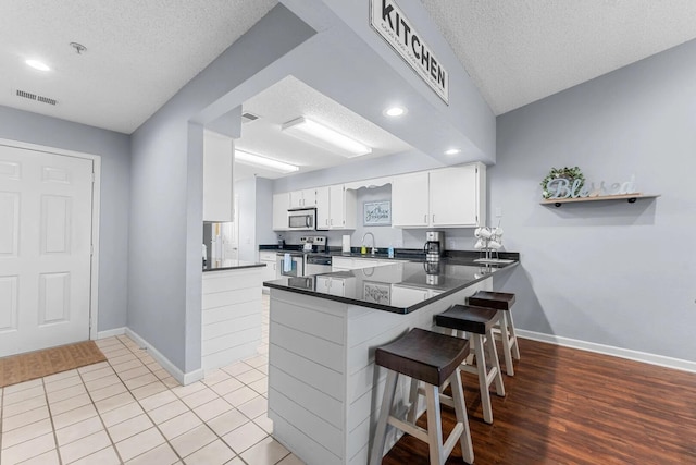 350 S Wildwood Dr Unit B-11, Branson, MO 65616 - kitchen featuring stainless steel appliances, a peninsula, baseboards, a textured ceiling, and white cabinetry