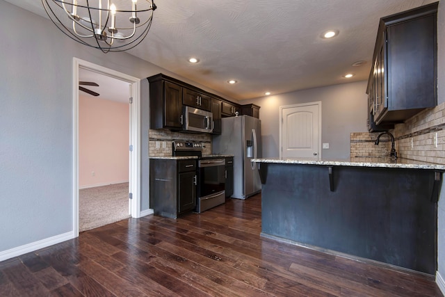 5048 S Fieldstone Rd, Battlefield, MO 65619 - kitchen featuring appliances with stainless steel finishes, decorative backsplash, dark wood finished floors, dark brown cabinets, and light stone countertops