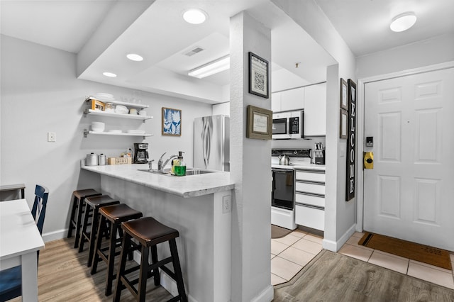 200 Golf View Dr Unit 3, Branson, MO 65616 - kitchen with stainless steel appliances, a sink, a breakfast bar, white cabinets, and light countertops
