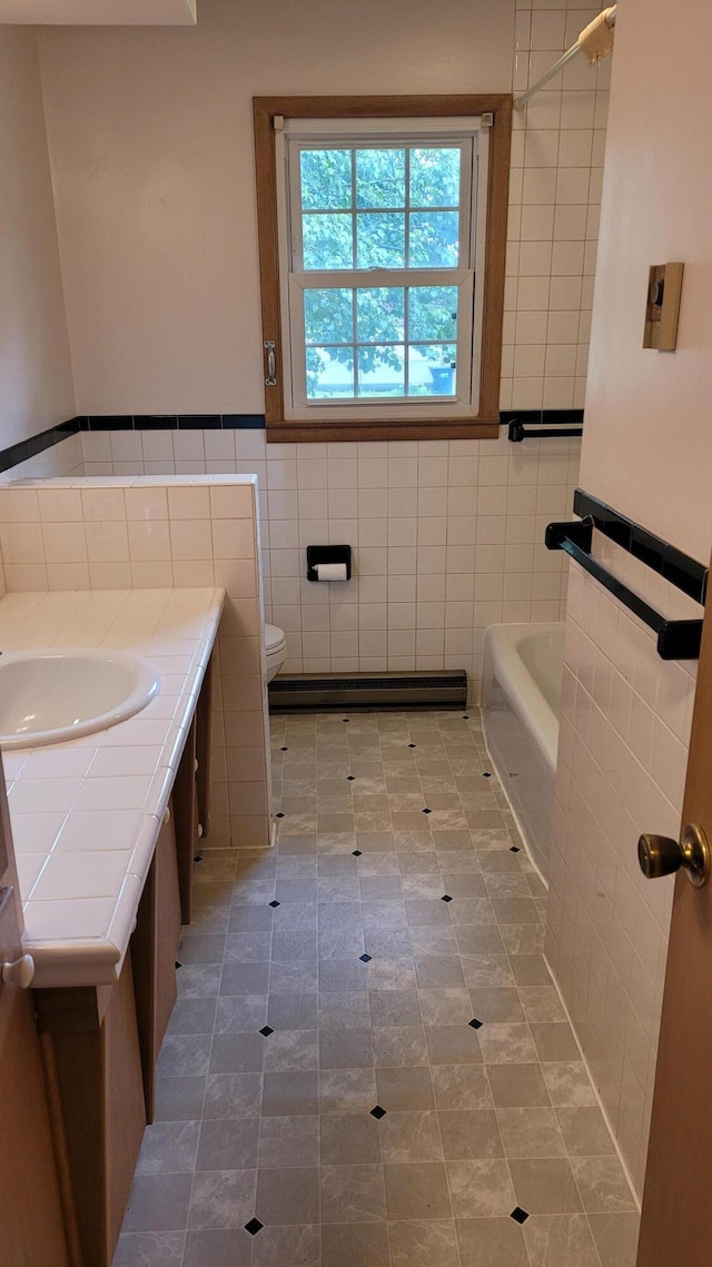 415 N Locust St, Marshfield, MO 65706 - full bath featuring tile walls, a baseboard radiator, a tub to relax in, vanity, and tile patterned flooring