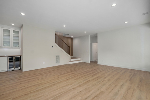 3725 E Woodhue St, Springfield, MO 65802 - unfurnished living room with beverage cooler, light wood-type flooring, recessed lighting, stairs, and a bar