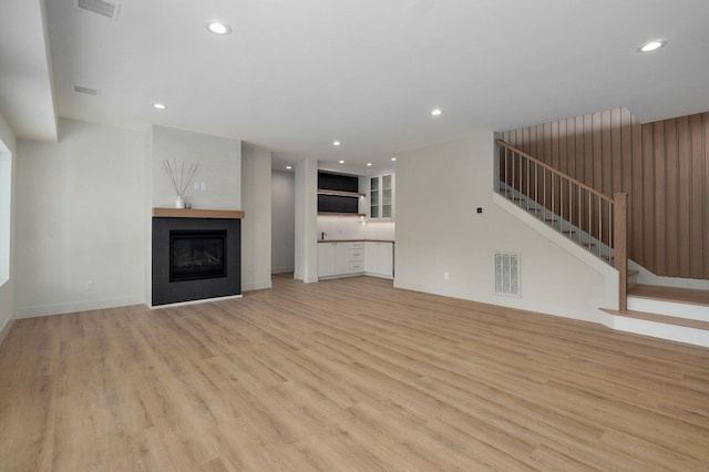 3725 E Woodhue St, Springfield, MO 65802 - unfurnished living room with light wood-style floors, recessed lighting, stairway, a glass covered fireplace, and baseboards