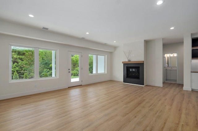 3725 E Woodhue St, Springfield, MO 65802 - unfurnished living room featuring baseboards, recessed lighting, light wood finished floors, and a glass covered fireplace