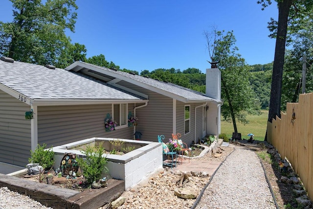 360 Cathy St, Branson, MO 65616 - view of side of home featuring roof with shingles, a chimney, and a garden