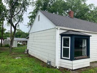 828 Stratford Pl, Neosho, MO 64850 - view of home's exterior with a chimney, a yard, and a shingled roof