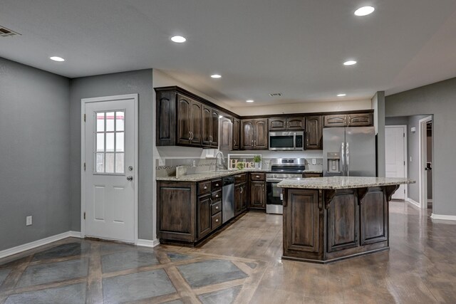 3383 Lusk Dr, Neosho, MO 64850 - kitchen featuring stainless steel appliances, dark brown cabinetry, baseboards, light stone countertops, and a sink