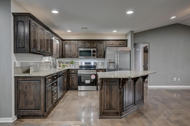 3383 Lusk Dr, Neosho, MO 64850 - kitchen featuring stainless steel appliances, dark brown cabinets, a kitchen island, light stone counters, and baseboards